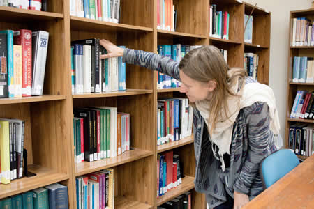 student at library shelves at ACCHS