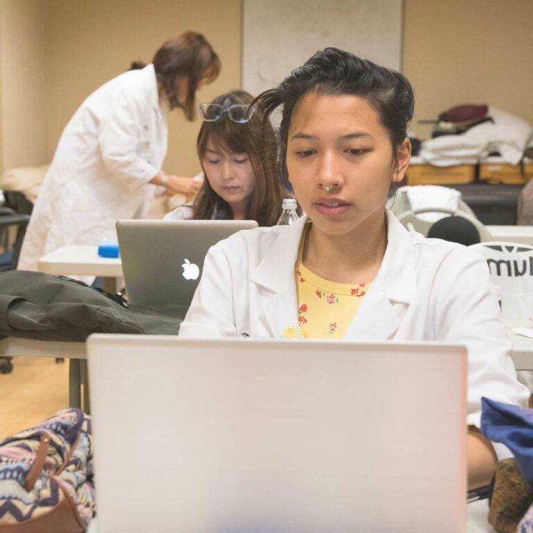 woman in lab coat working on laptop