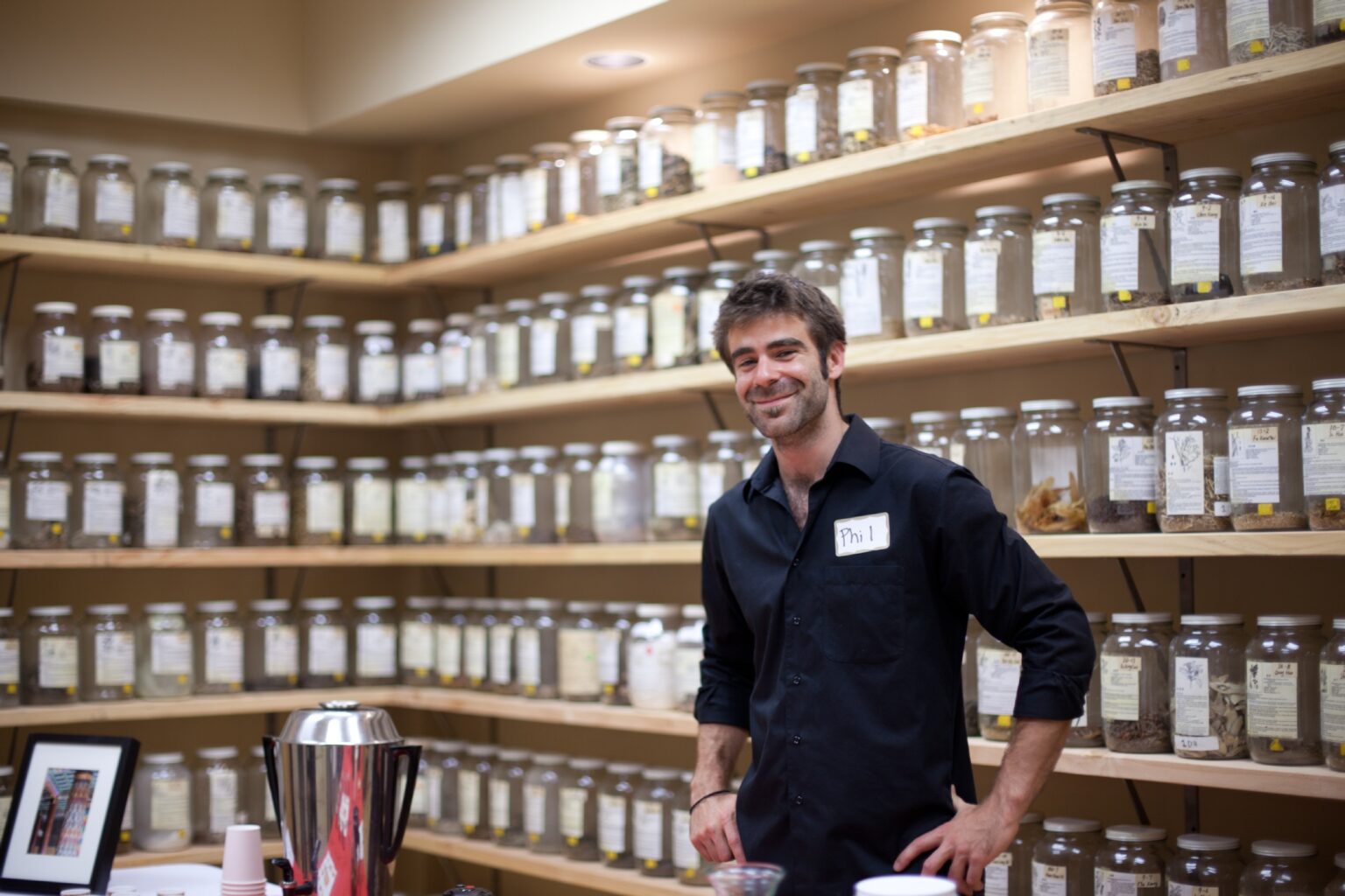 man standing in front of many shelves of herb containers