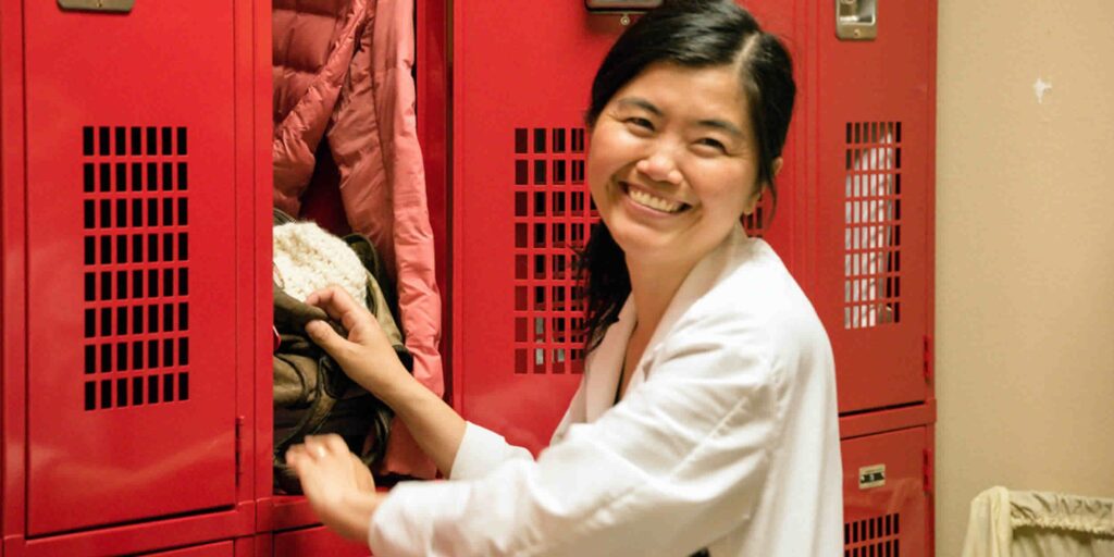 woman in white coat, smiling at locker