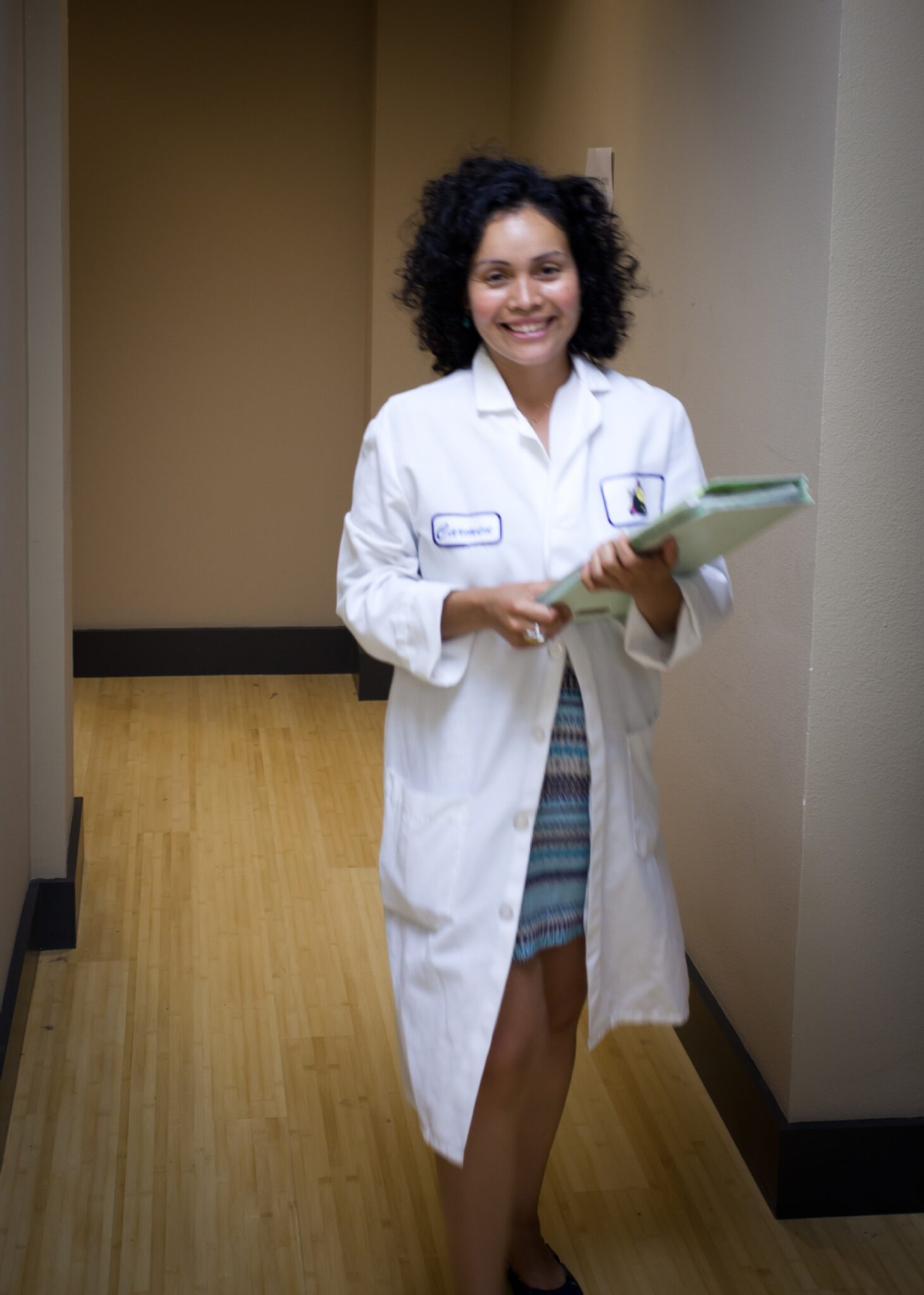 woman wearing lab coat smiling and holding clipboard