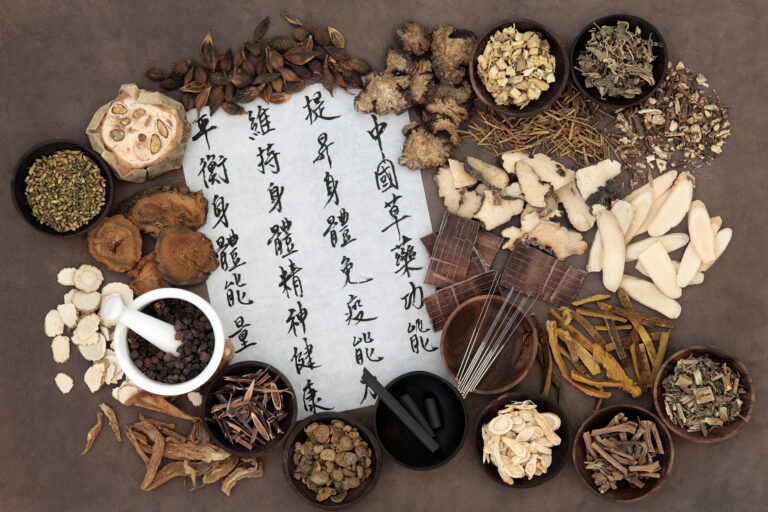 Chinese herbal medicine selection, acupuncture needles, moxa sticks and mandarin calligraphy script. Translation describes chinese herbal medicine as increasing the bodys ability to maintain body and spirit health and balance energy.