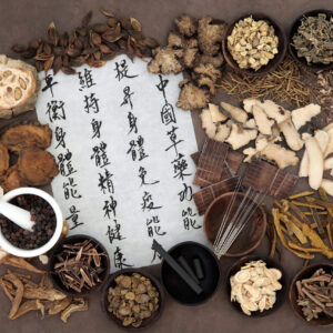 Chinese herbal medicine selection, acupuncture needles, moxa sticks and mandarin calligraphy script. Translation describes chinese herbal medicine as increasing the bodys ability to maintain body and spirit health and balance energy.